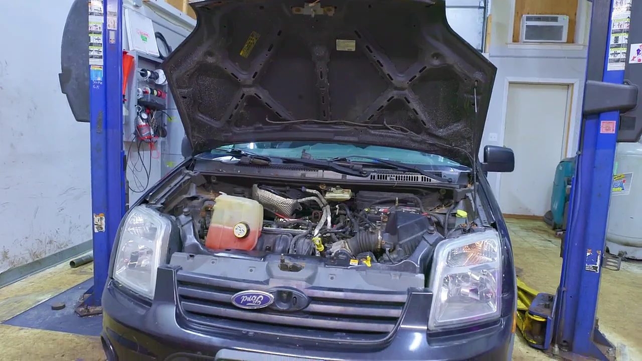 A Ford Transit Connect on the lift with its hood up