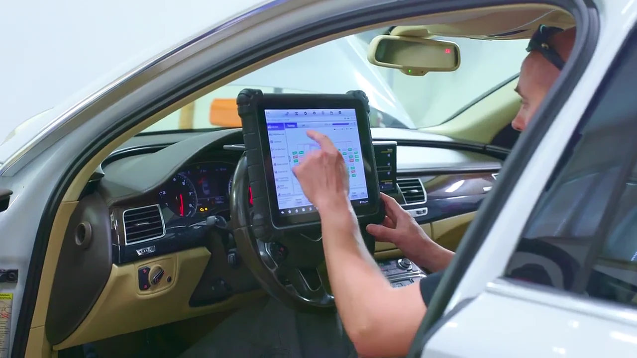 A technician running a scan tablet from the driver's seat